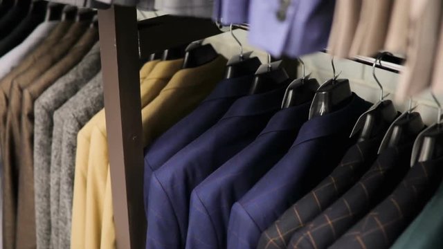 Row of men suit jackets on hangers. Collection of new beautiful clothes hanging on hangers in a shop