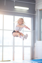 sportsman jumping on a trampoline and doing split indoors