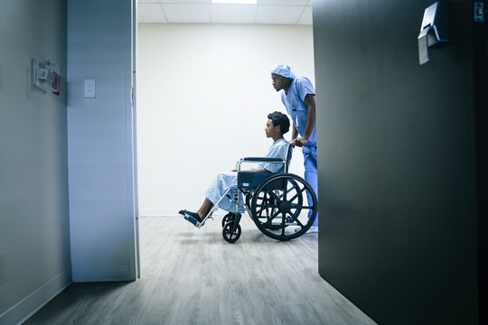 Nurse pushing boy on wheelchair in hospital corridor