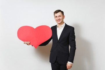 Young handsome man in suit holding big red heart isolated on white background. Copy space, advertisement. Place for text. St. Valentine's Day, International Women's Day, birthday, holiday concept.