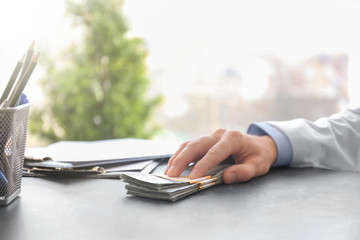 Fototapeta premium Doctor with bribe at workplace, closeup