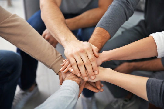 Young people putting hands together during group therapy, closeup