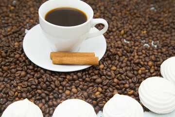 Coffee cup, straws, marshmallows and coffee beans on wooden background