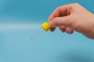 on a blue background, male hand, falling drops from the pipette