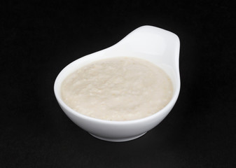Horseradish sauce in white bowl isolated on black background