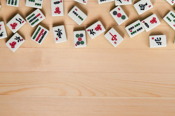 White-green tiles for mahjong on a brown wooden background. Empty space from below