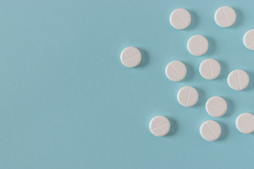 White pills on the bright blue surface. Top view.
