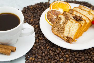 Coffee cup, dried orange and coffee beans on white stone background