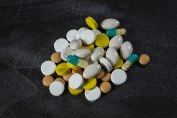 A pile of pills and capsules on a black table