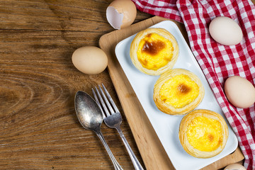 Delicious freshly baked egg tarts on wooden background