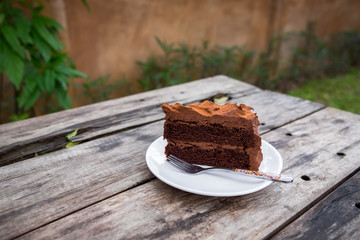 Close-up of chocolate cake on wooden table in outdoor garden. Concept sweets enjoy eating.