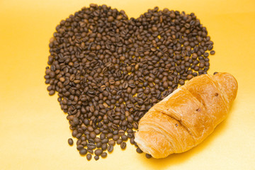 I love coffee concept. Coffee beans and croissant on yellow background. Copyspace and closeup