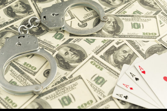  handcuffs, banknotes of dollars, four ace of playing cards. ban on gambling