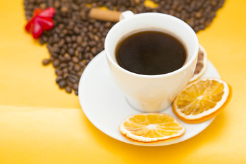 I love coffee concept. Coffee cup, beans and sun dried orange on yellow background