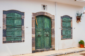 green shutters and doors on a white wall, close up