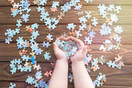 puzzles in the hands of a child on a wooden background.