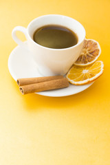 I love coffee concept. Coffee cup and sun dried orange on yellow background. Copyspace and closeup