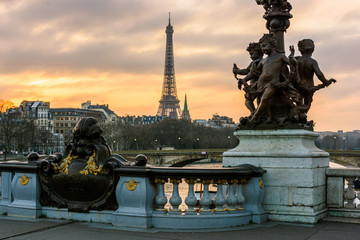 Fototapeta na wymiar View of the Eiffel tower from the Pont Alexandre III at sunset with the cherubs ornamenting one of its Art Nouveau street lamp in the foreground.