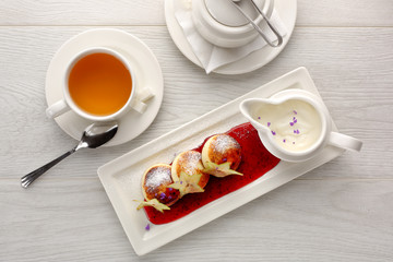 Cottage cheese pancakes with strawberry jam, sour cream on white wooden background, breakfast or lunch, tea