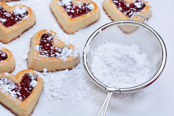Heart cookies with strainer sugar on baking paper