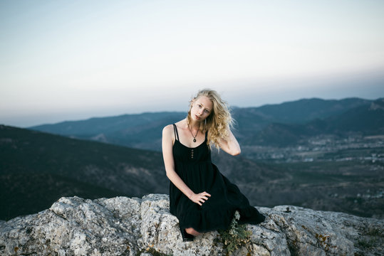 Caucasian woman sitting on rock near mountains