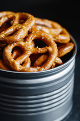 Crunchy pretzels appetizer in a metal jar on a black table. Mystic light style.