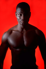 portrait of an african man shirtless on red background