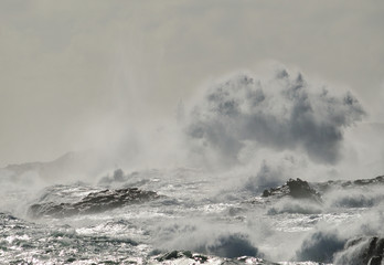 Rough sea on the coast, big wave when breaking and blurred silhouette of lighthouse in the background, Telde, Canary islands