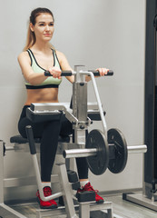 Fototapeta premium Young girl makes exercises at the gym