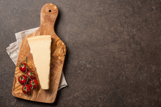 Parmesan cheese and tomatoes on wooden cutting board