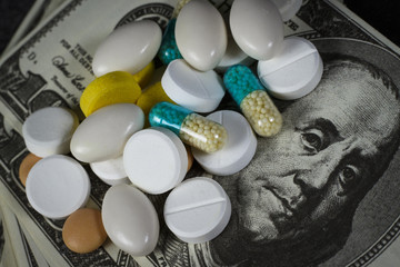 Many pills on on a pile of dollars