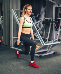 Fototapeta na wymiar Young girl makes exercises at the gym