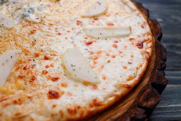 Delicious quattro formaggi cheese pizza with pear on wood, close up. Italian restaurant concept