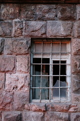Fototapeta na wymiar Abandoned window with bars in pink tuf wall