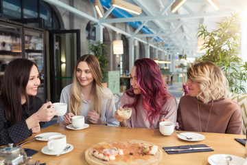 Gossipgirls, freindship concept. Female friends with tea and coffee speaking in cafe, gossip and news. Smiling women laughing, talking and smiling together in coffee shop