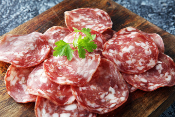 thinly sliced salami on a wooden texture on the background.
