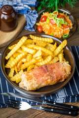 Fried chicken breast stuffed with mushrooms and cheese wrapped in ham served with fries and salad.