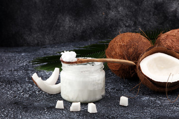 coconut oil and fresh coconuts on grey background.