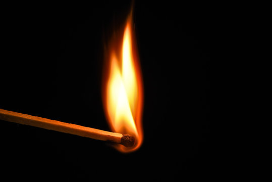 Fire burning on matchstick. Isolated on black background.