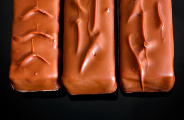 Three chocolate bars in a row. Black background.