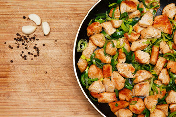roasted chicken with leek in a frying pan on wooden background. grilled chicken. Homemade food. flat lay, top view. copy space for your text