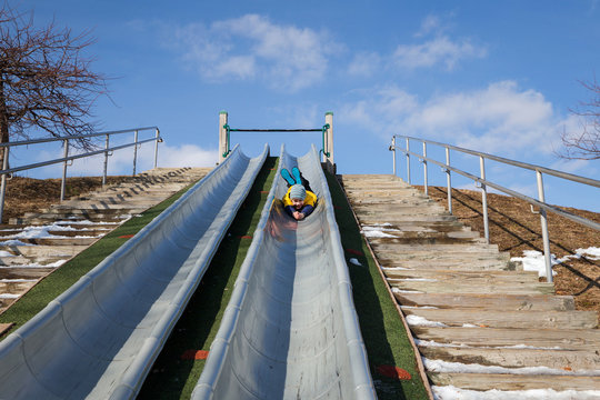 Boy Having Fun Sliding Down On The Playground. Kid Playing Outdoors. Copy Space For Your Text