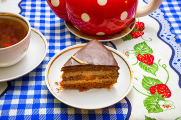 A piece of chocolate cake on a white saucer on a blue tablecloth