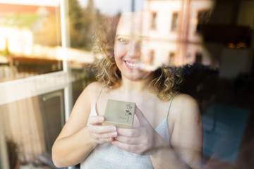 ​Beautiful curly young woman holding a box of surprise with in for love text during lookin out...