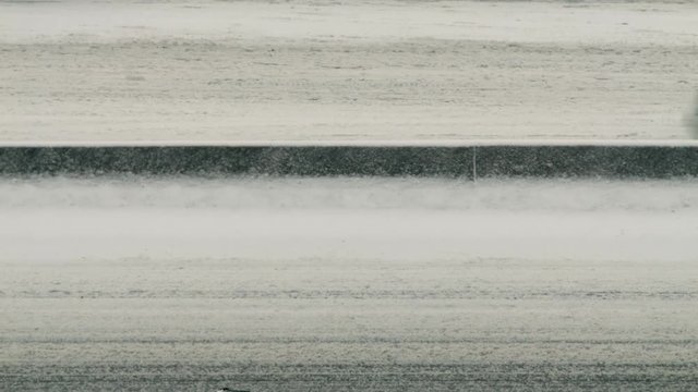 Cars move in both directions along snowy highway during snow storm.