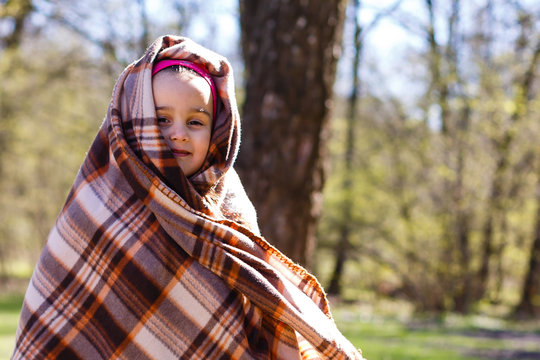 Cute twin sisters wrapped in check plaid. Colorful autumn park.