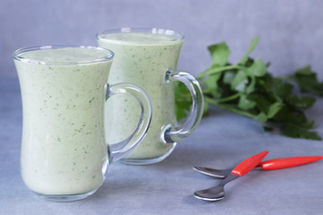 Green organic smoothies in glass jars on a gray background.