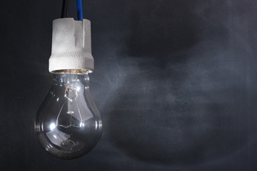 Light bulb on electric cable with shadow in dark room