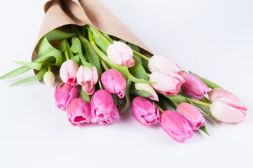 pink tulips wrapped in brown paper on a white background