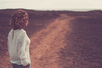 Beautiful woman walking on a path in the desert near the ocean